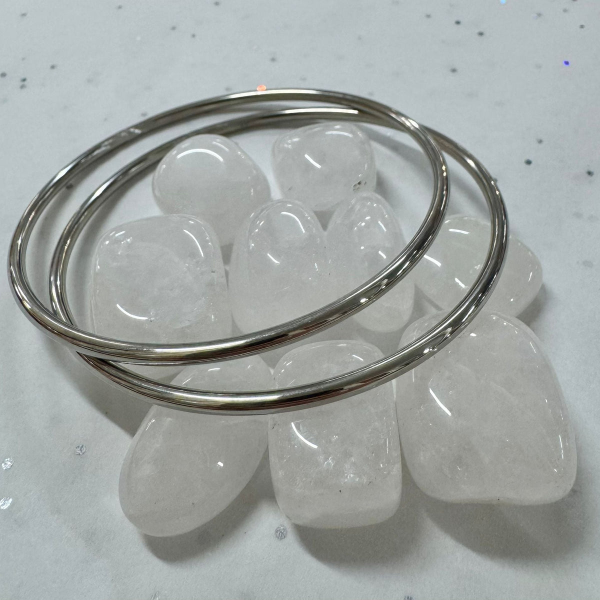 Silver bangles on a white stone surface