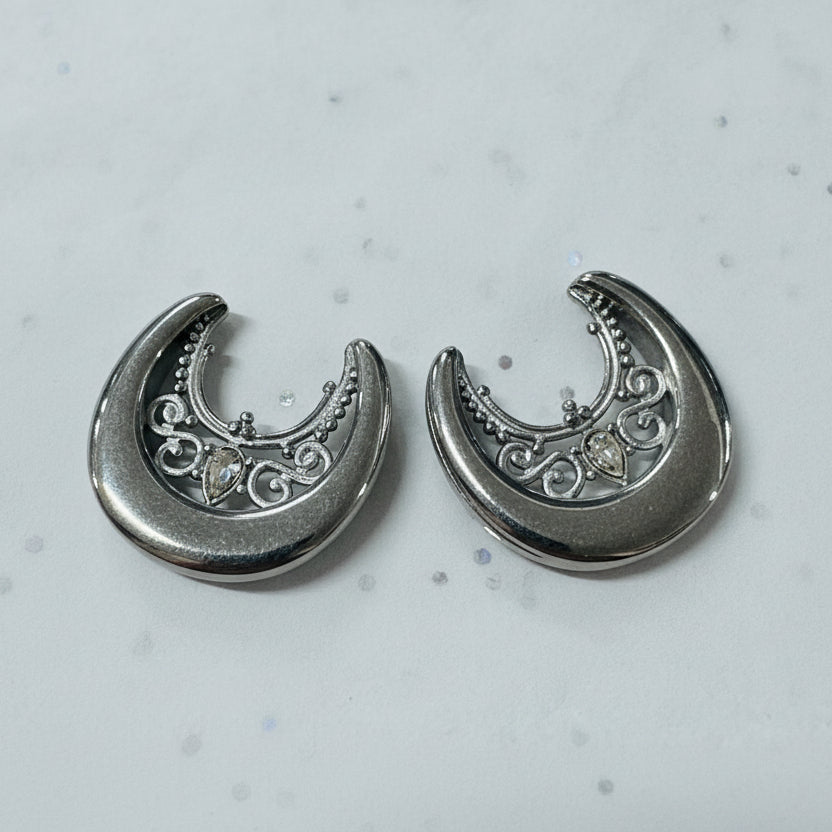 Silver crescent moon earrings on a light gray background