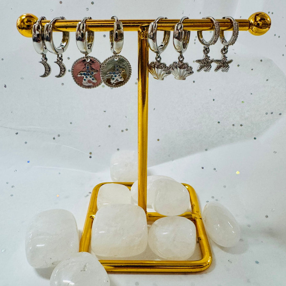 Gold earring stand with various earrings on a white background