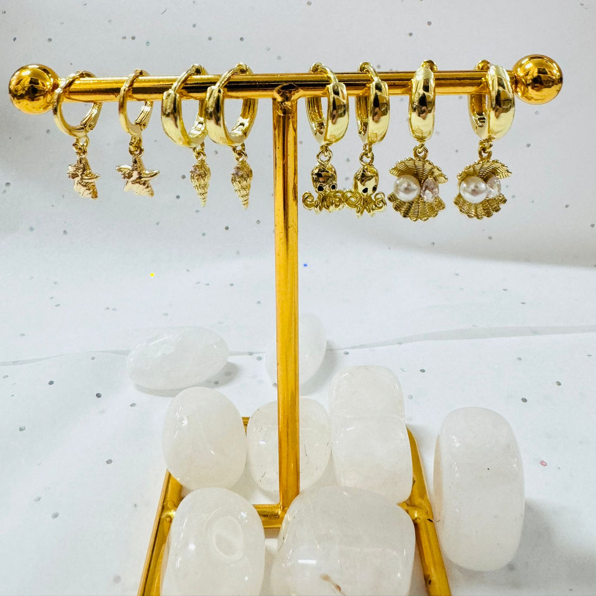 Gold earring stand with various earrings on a white background