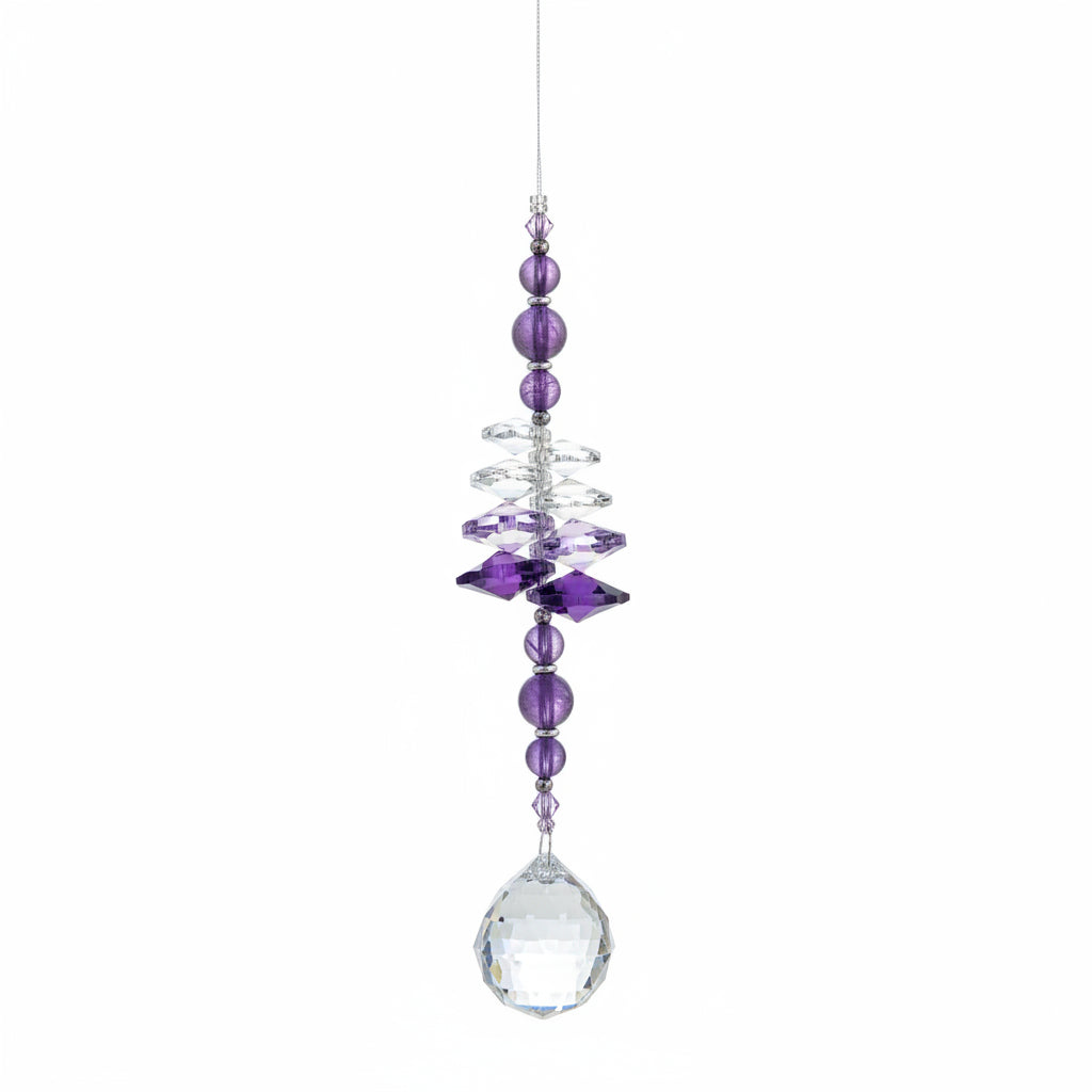 A beaded hanging ornament or suncatcher with purple and clear crystals, suspended against a wooden background.