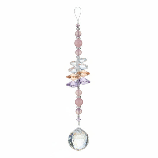 A beaded suncatcher ornament with a large faceted iridescent crystal ball at the bottom, hanging from a purple retail tag on a wooden floor.