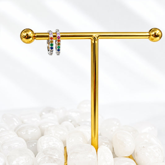 silver earring stand with a pair of earrings on a white surface with rocks.