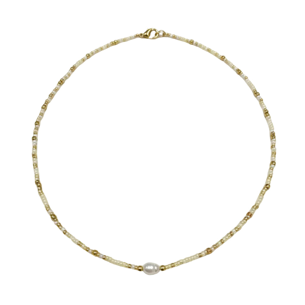 Gold necklace with a pearl pendant worn by a person.