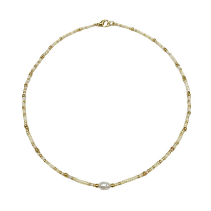 Gold necklace with a pearl pendant worn by a person.