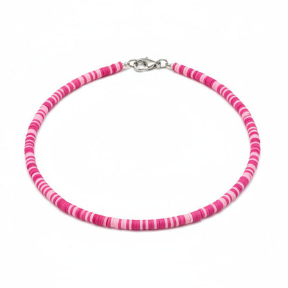 Person wearing a pink beaded necklace against a blurred background