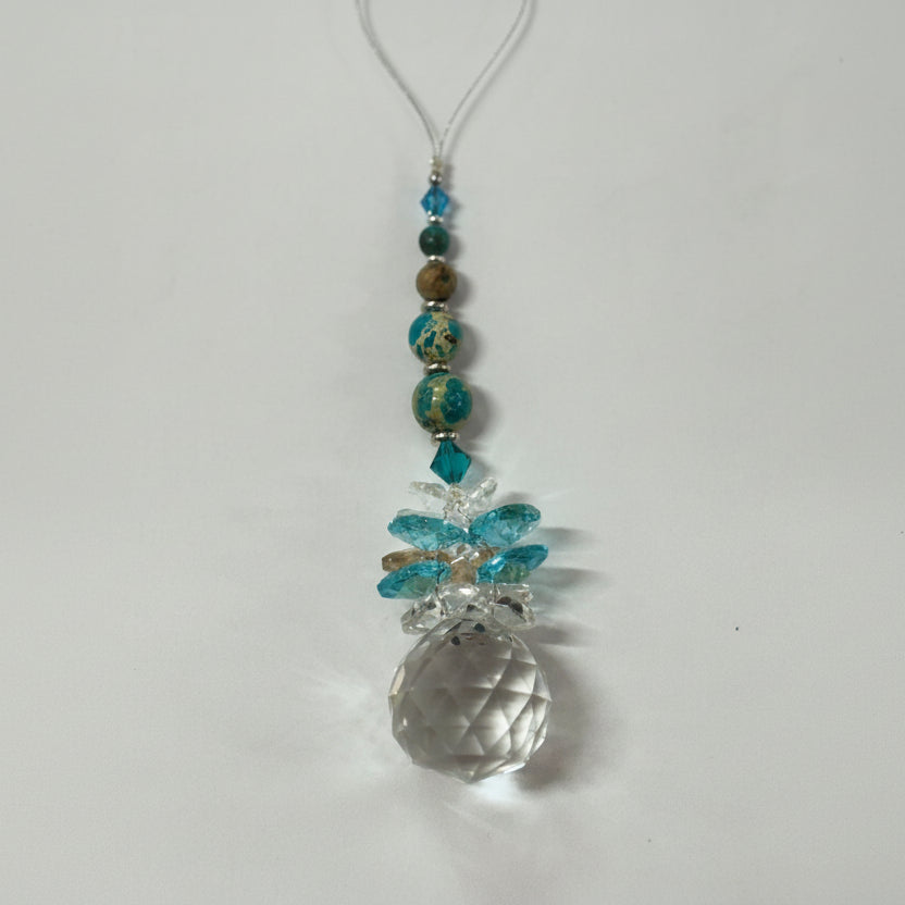 Decorative hanging ornament with beads and a large crystal-like bead on a white background.
