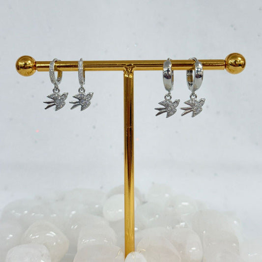 Silver earrings with leaf designs on a gold display stand against a white background.