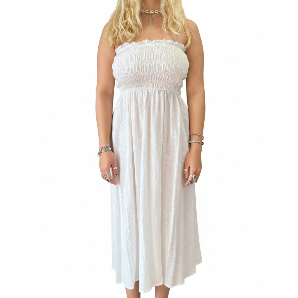 Person wearing a white strapless dress in a store setting with plants and shelves.