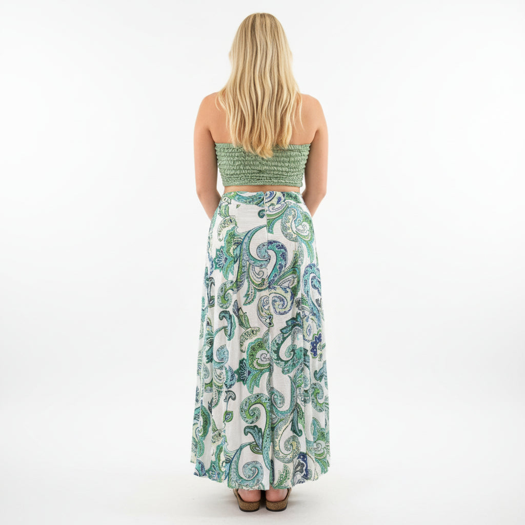 Person wearing a green and white patterned dress in a store setting with plants and decor.