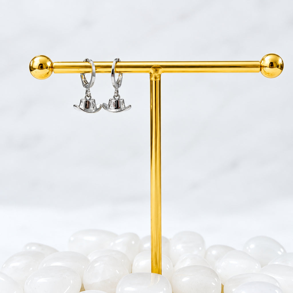 Gold earring stand with silver earrings on a white background
