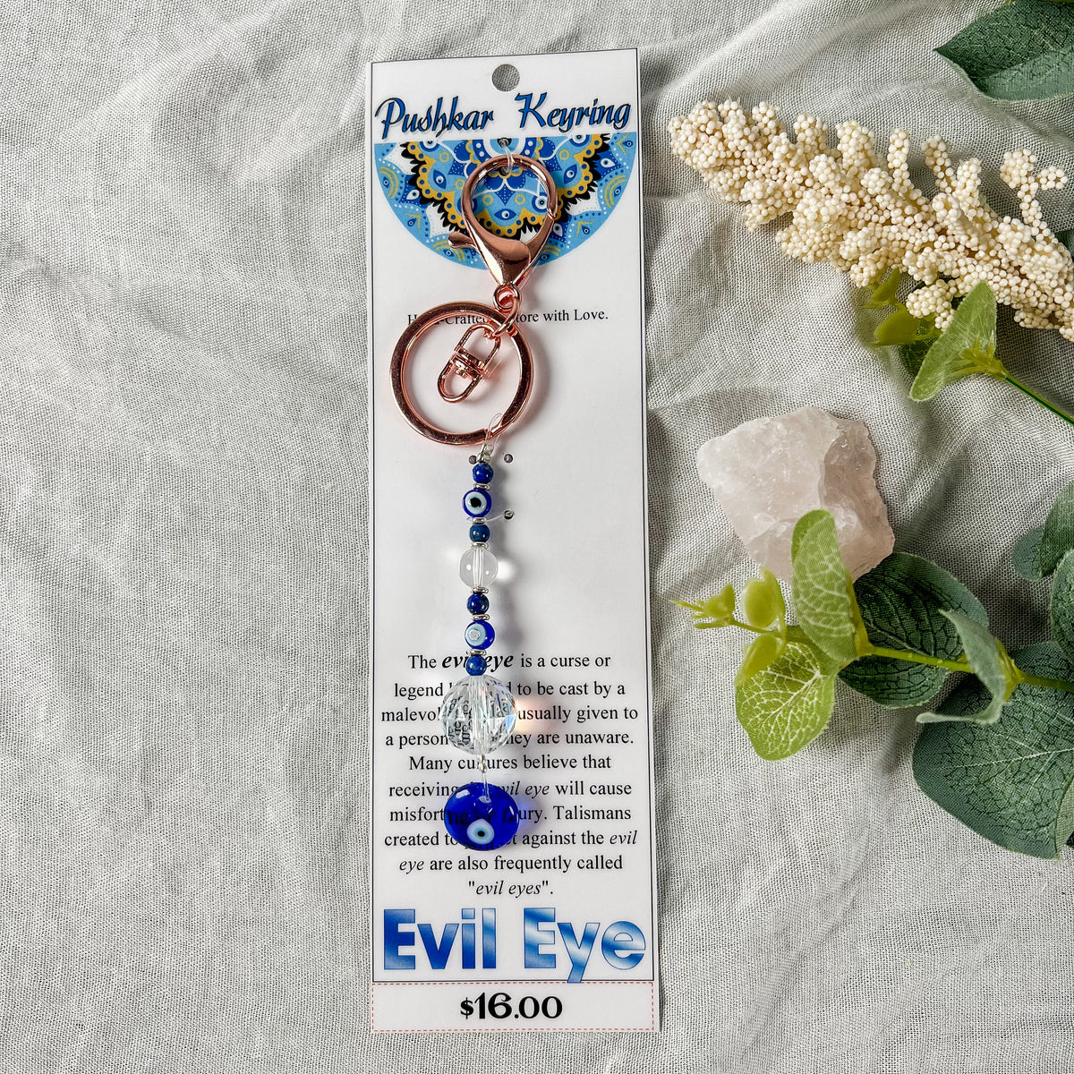 A turquoise and copper key ring with an evil eye design, displayed on a card.
