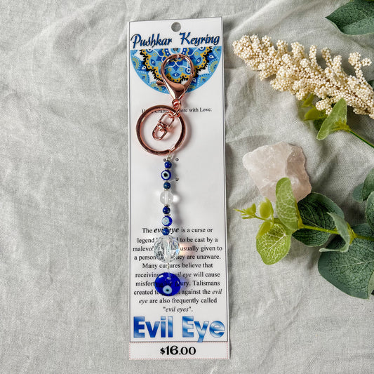 A turquoise and copper key ring with an evil eye design, displayed on a card.