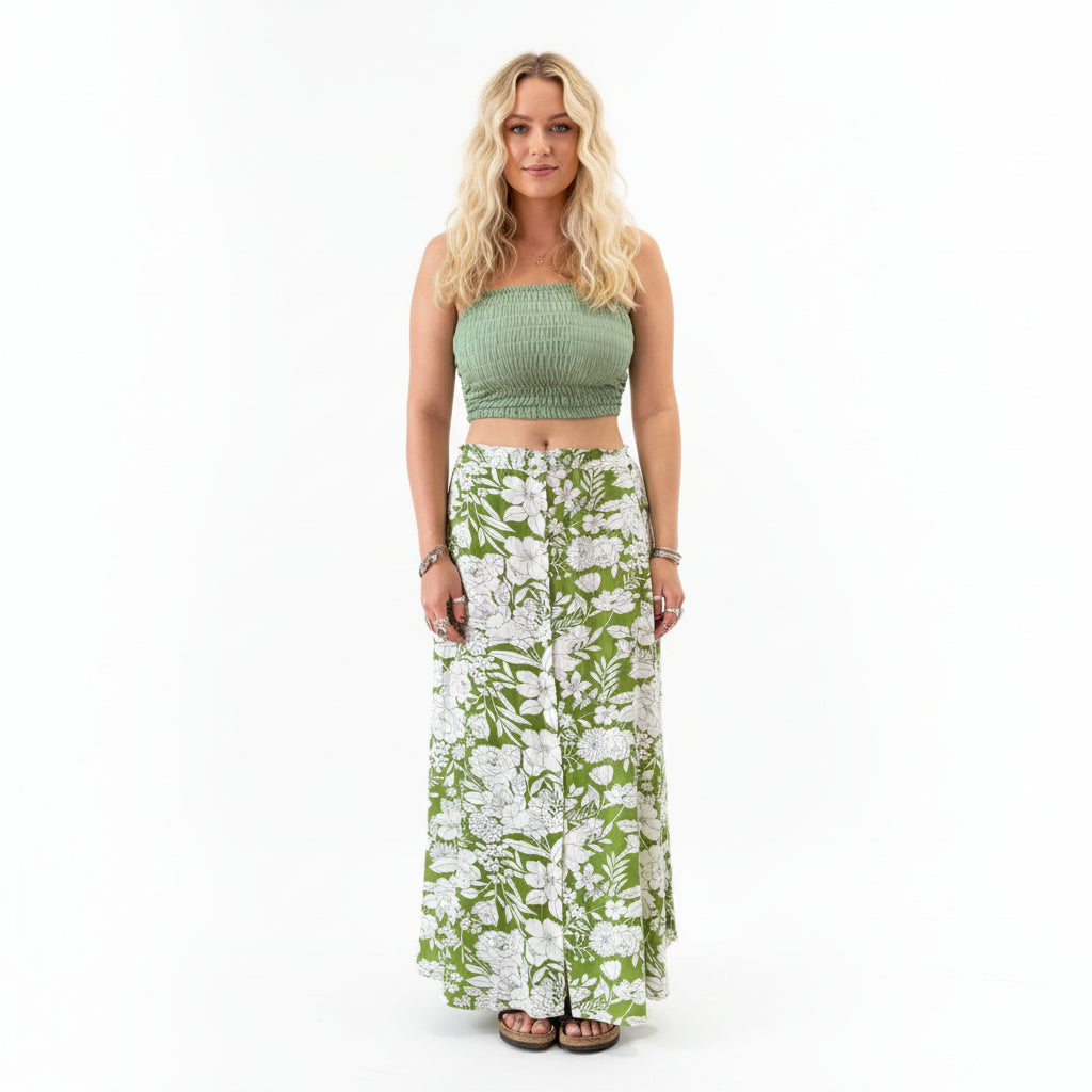 Person wearing a green top and floral skirt in a store setting with plants and shelves.