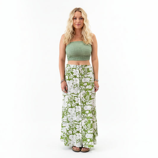 Person wearing a green top and floral skirt in a store setting with plants and shelves.