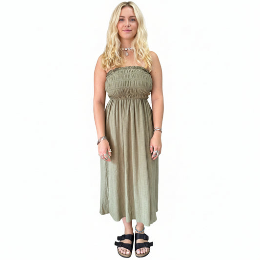 Woman wearing a green dress standing in a store with plants and shelves in the background