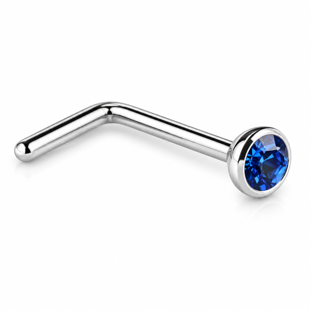 A silver-colored curved barbell nose stud with a faceted blue gemstone in a bezel setting, shown on a plain white background.