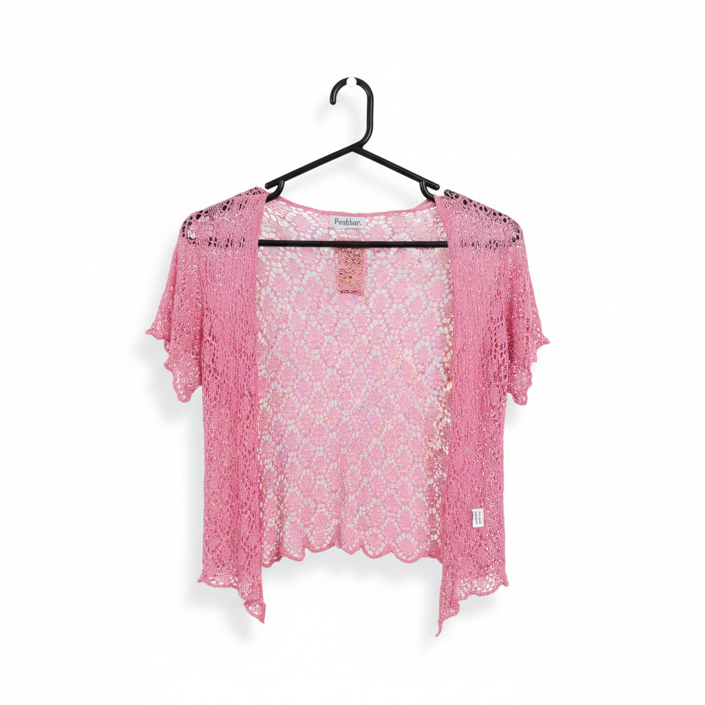 A pink open-front crochet cardigan with short sleeves and a scalloped hem, hanging on a black hanger in a retail store.